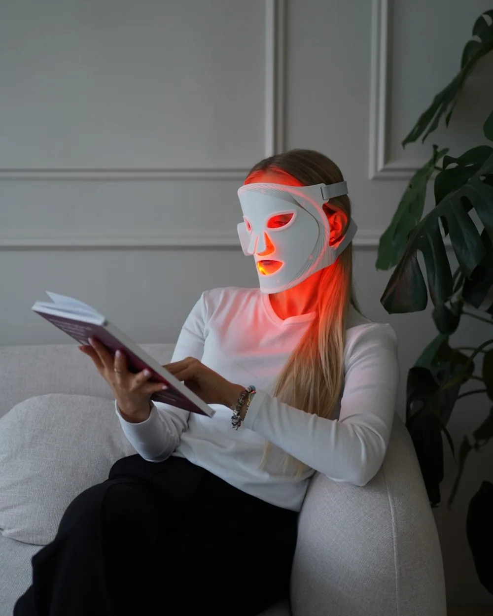 Kobieta czytająca w fotelu z białą maską BELUME